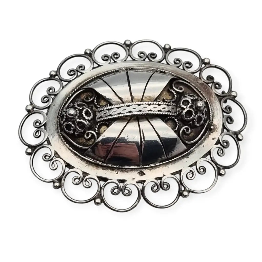 Oval silver brooch with detailed folk filigree and Art Nouveau design.